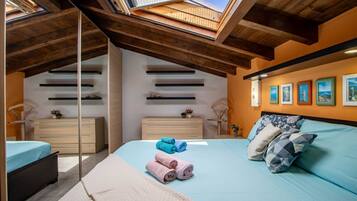 Ein Schlafzimmer mit Oberlicht, einem Bett mit aufgerollten Handtüchern, einem Schminktisch und Kunstwerken an der Wand.
