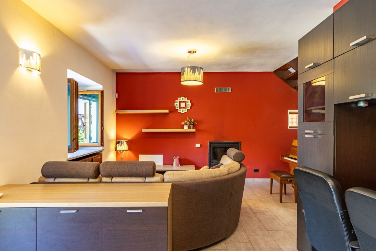 En moderne stue med en kurvet sofa, et spisebord og et køkkenområde med skabe.