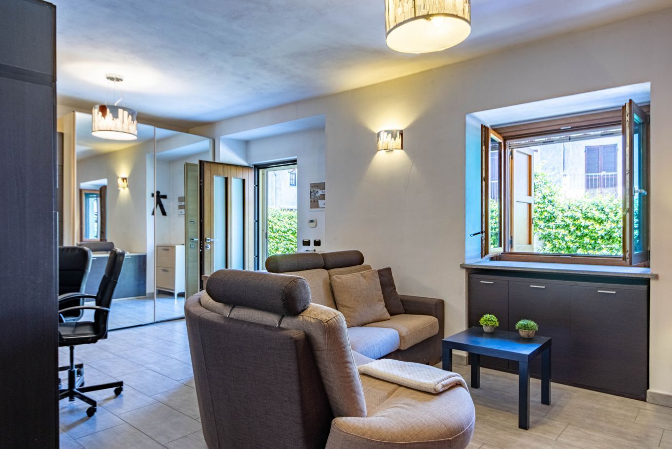 Un salón moderno con un sofá, una mesita y una ventana con vistas a zonas verdes.