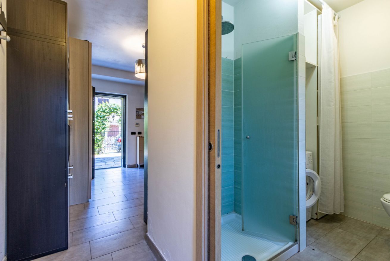 Een moderne badkamer met een douchecabine van glas, een toilet en een zichtbare deur naar een andere ruimte.