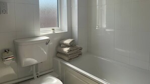 A bathroom with a toilet, a sink, a window, and a bathtub. - One Bedroom Apartment Sleeps 2 With Free Parking (London)