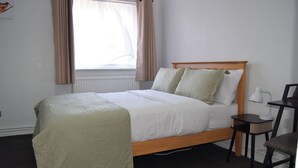 A bedroom with a single bed, a bedside table, a chair, and a window with curtains. - One Bedroom Apartment Sleeps 2 With Free Parking (London)