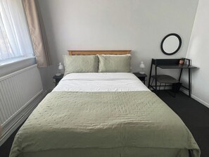 Ein Hotelzimmer mit einem Bett, Nachttischen, einem Schreibtisch und einem Stuhl.