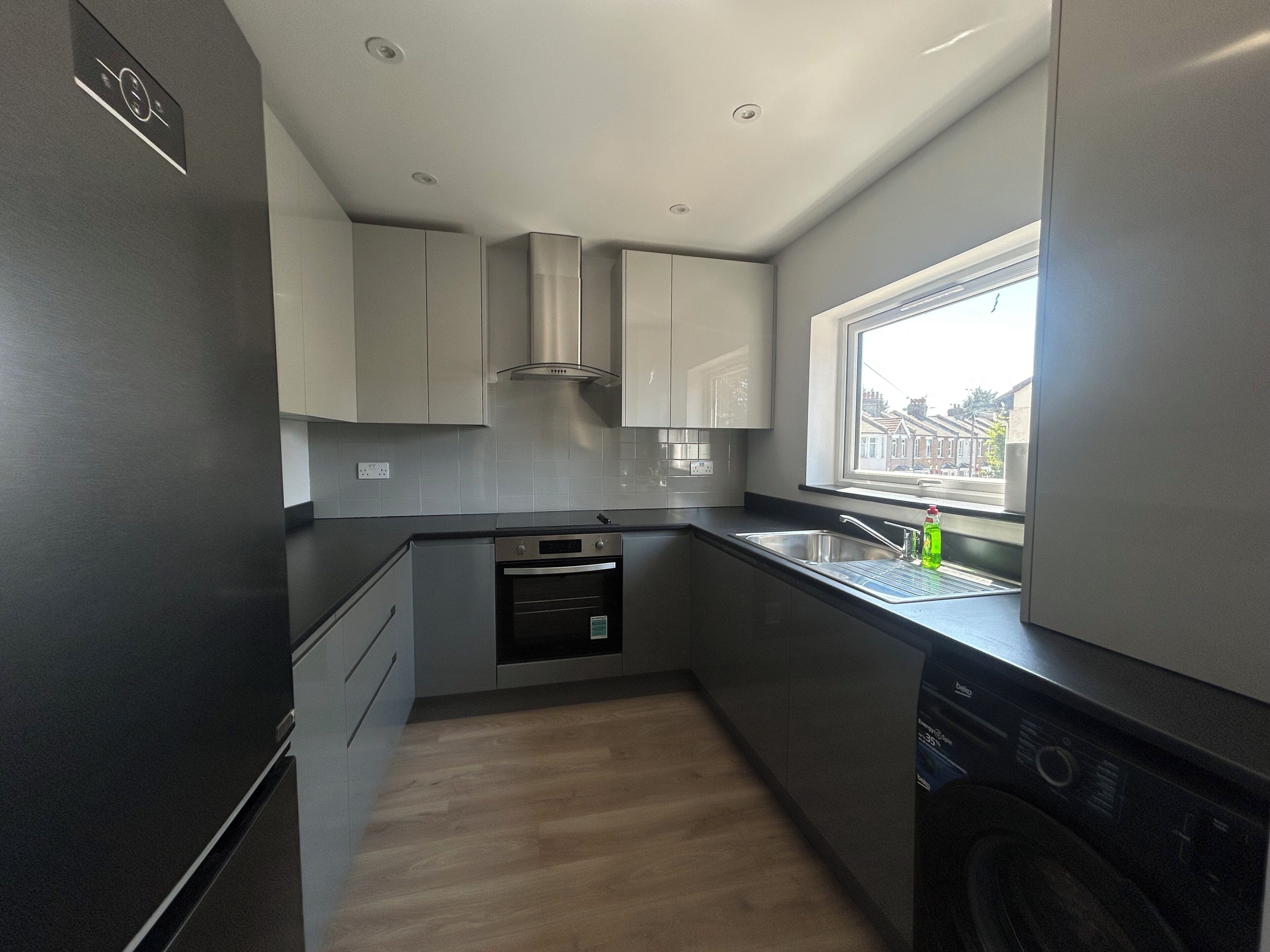 A modern kitchen with built-in appliances, a window, and a view of the street.