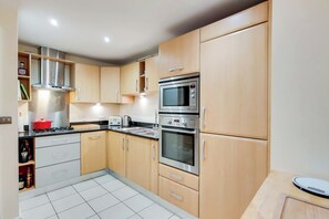 A modern kitchen with stainless steel appliances, wooden cabinets, and a tiled floor. - Newly Refurbished 3BDR Home with Parking (Greater London)