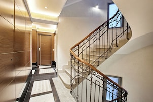 Un interior moderno con una puerta de madera, una escalera con barandillas metálicas y un suelo con diseño.