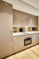 Una cocina moderna con horno empotrado, pileta de acero inoxidable y un amplio ventanal.