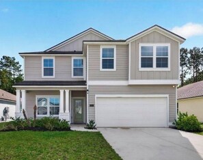A two-story residential house with a front garage and a small front porch. - St. Augustine Sanctuary: Spacious Modern 4-Bed Getaway with Resort Amenities (St. Augustine)