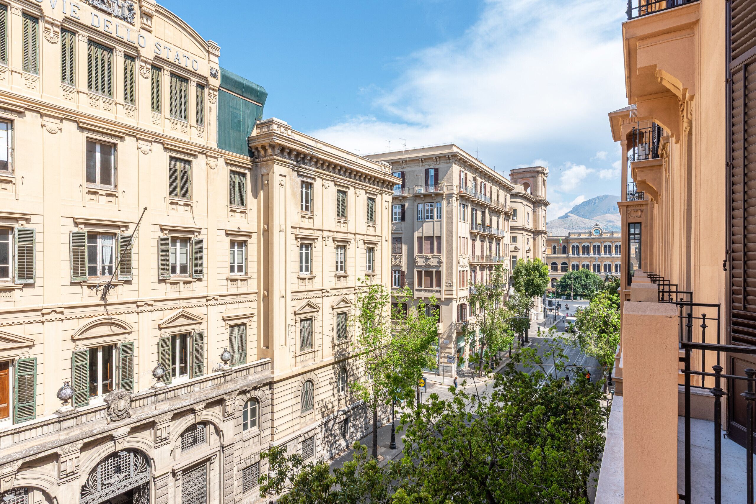 A street view with historic buildings, a clear sky, and a mountain in the background.