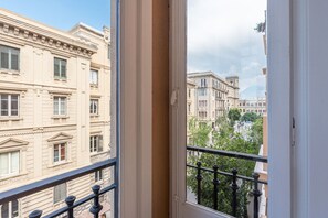 Blick von einem Balkon mit Metallgeländer auf eine Straße mit historischen Gebäuden.