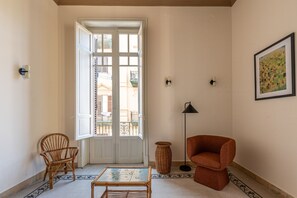 A room with a white door, wicker furniture, a floor lamp, and a framed picture on the wall. - Roma 1923 - Casa Verde by Wonderful Italy (Palermo)