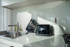 A kitchen with a stainless steel sink, a toaster, and a knife block. - Skyline Serenity @ Olympic Park (Sydney Olympic Park)