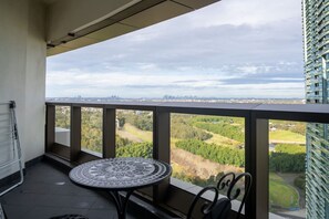 A balcony with a table and chairs, overlooking a cityscape and greenery. - Skyline Serenity @ Olympic Park (Sydney Olympic Park)