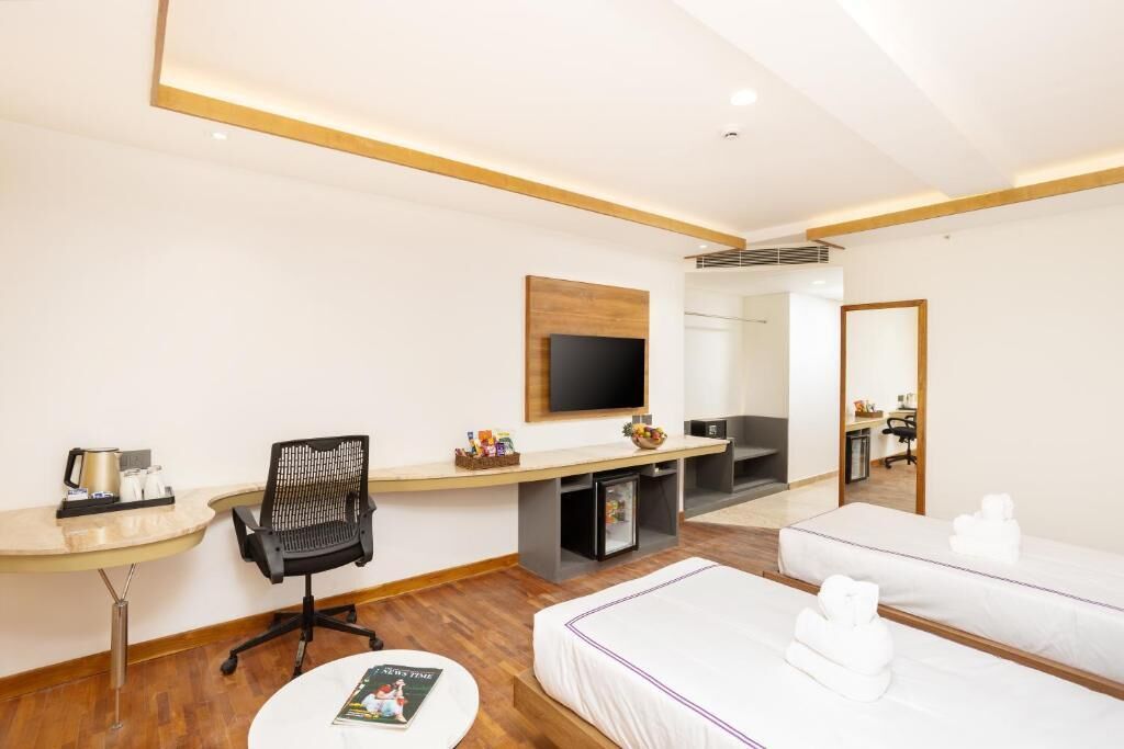 Une chambre d’hôtel équipée d’un bureau, d’une chaise, d’une télévision et de deux lits.