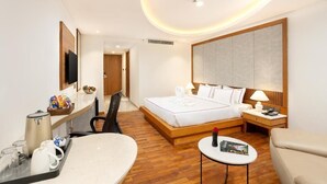 A hotel room with a bed, bedside table, chair, and a small table with a magazine. - Hotel Explora Calicut by Nova (Kozhikode)