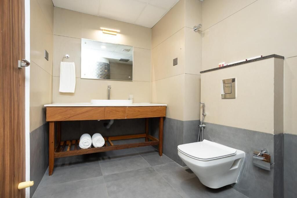 A modern bathroom with a wooden vanity, a white toilet, and a mirror above the sink.