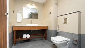 A modern bathroom with a wooden vanity, a white toilet, and a mirror above the sink.