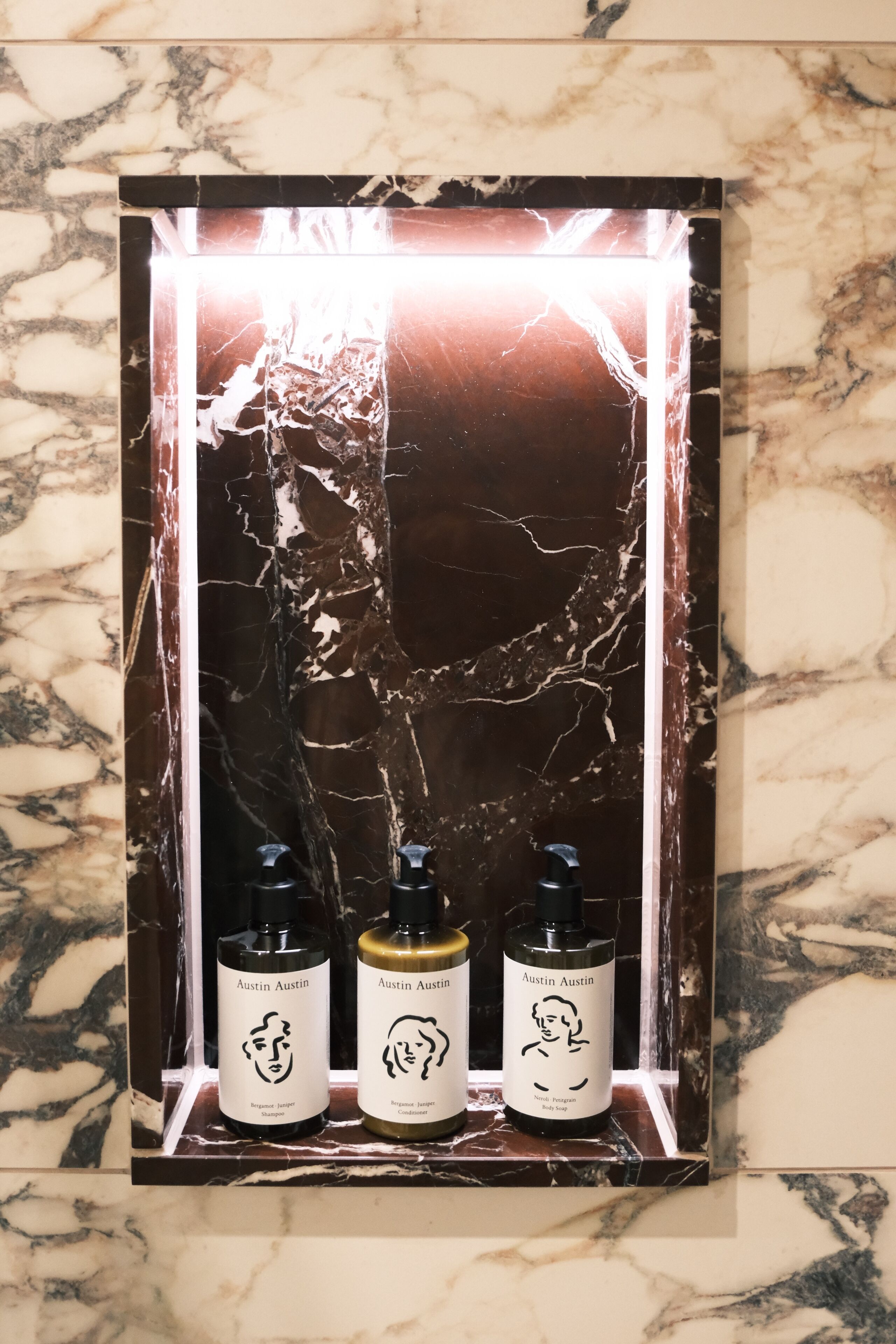 A display shelf with three bottles of Austin Austin products against a marble background.