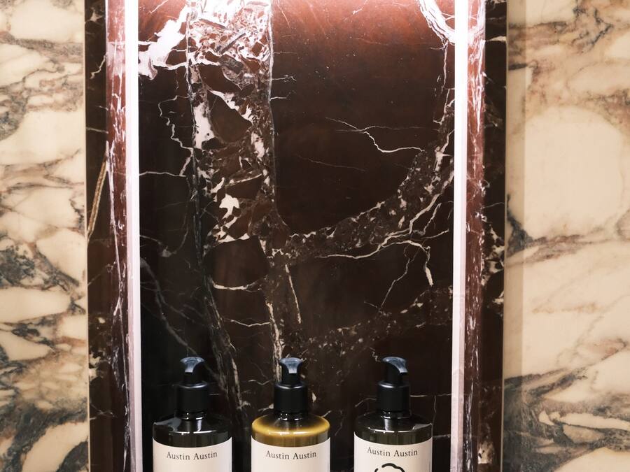 A display shelf with three bottles of Austin Austin products against a marble background.