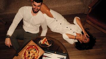 Una persona recostada en el suelo con una caja de pizza y un juego de mesa cerca.