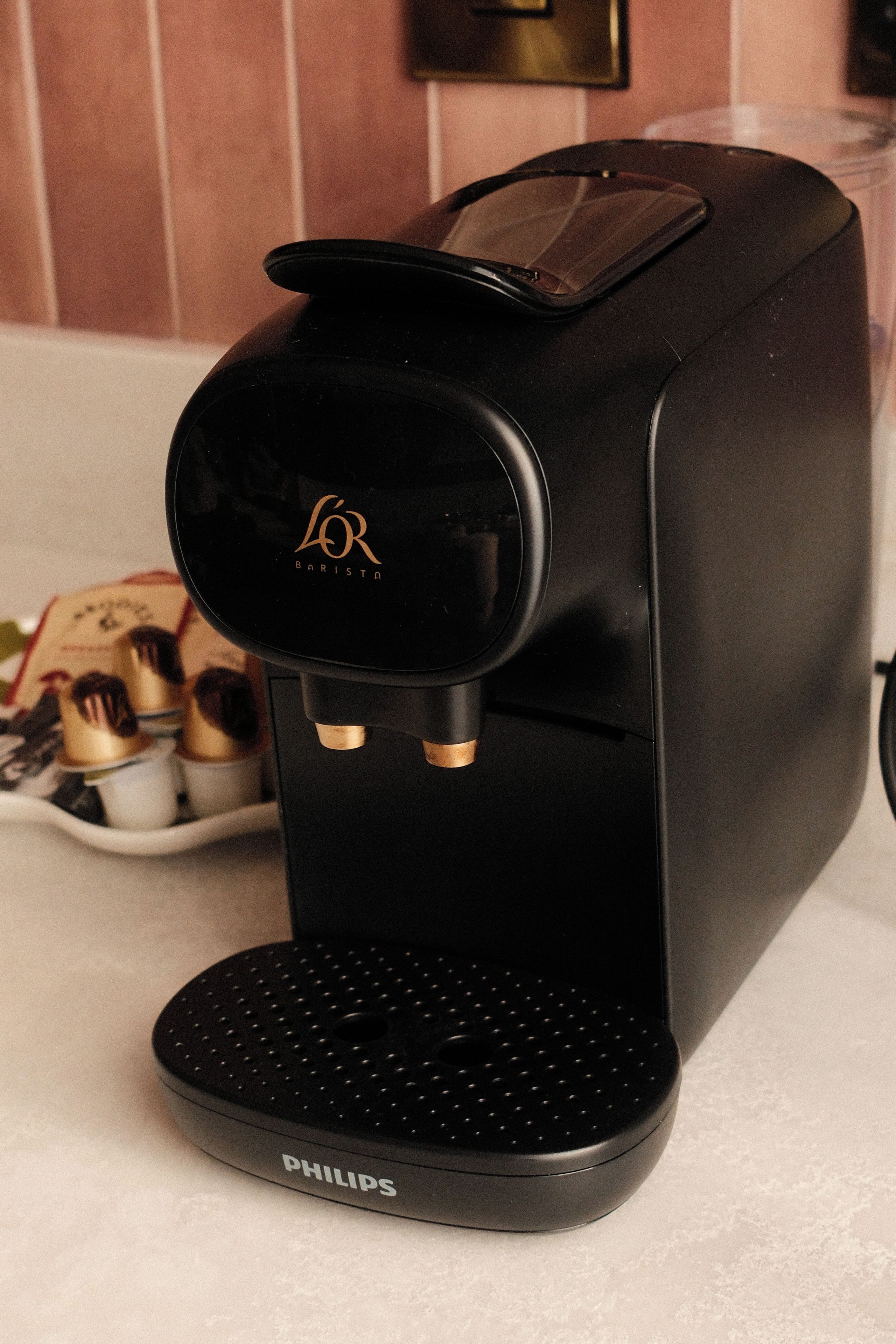 A black coffee machine with a brand logo on the front, a control panel, and a drip tray.
