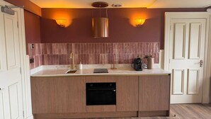 A modern kitchen with a built-in oven, a sink, and a coffee maker. - Meus Apartments (Edinburgh)