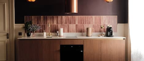 A modern kitchen with a wooden cabinet, a dishwasher, a coffee maker, and a kettle.
