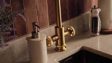 Eine Küche mit einem goldenen Wasserhahn, einem weißen Seifenspender und einem Glasbehälter mit Deckel.