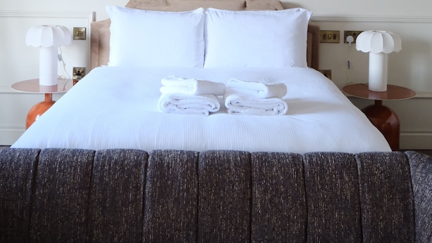 A hotel room with a large bed, two bedside tables, a painting on the wall, and a ceiling fan. - Meus Apartments (Edinburgh)