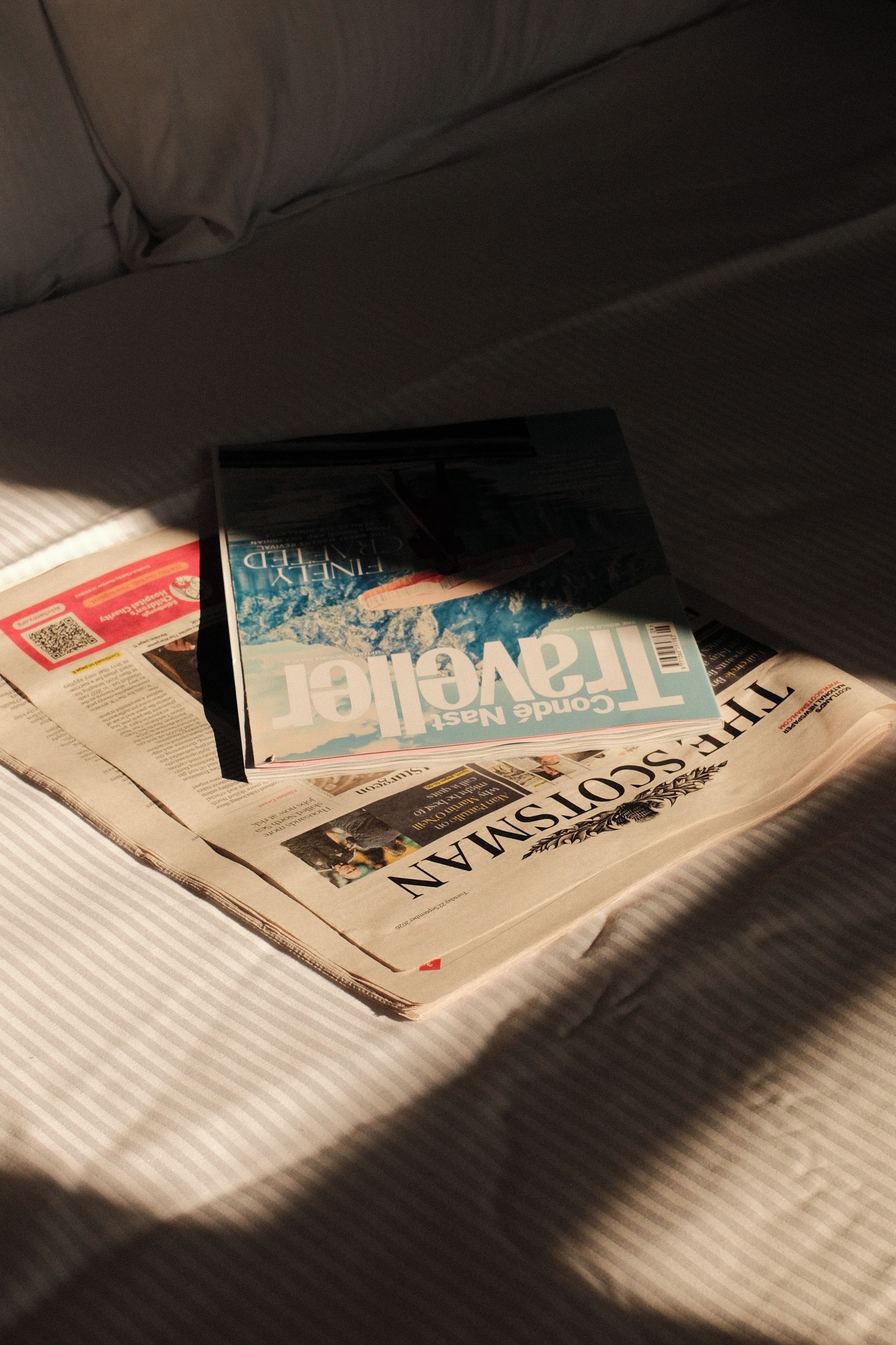 Una revista sobre la cama con una colcha a rayas.