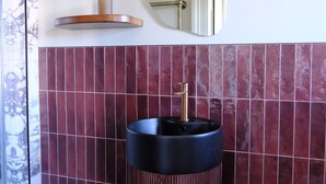 A bathroom with a black sink, a mirror, and a red-tiled wall. - Meus Apartments (Edinburgh)