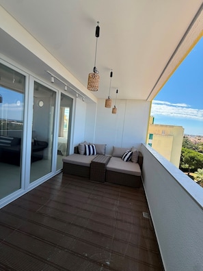 A balcony with a sofa, wicker pendant lights, and a view of the city. - Reformed Vintage Top Floor Stunning Views by Bento Box (Quarteira)