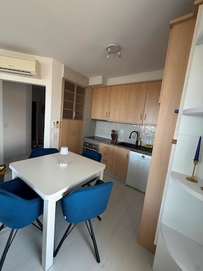 A compact kitchen with a dining area, including a table and chairs, a built-in oven, and a dishwasher. - Reformed Vintage Top Floor Stunning Views by Bento Box (Quarteira)