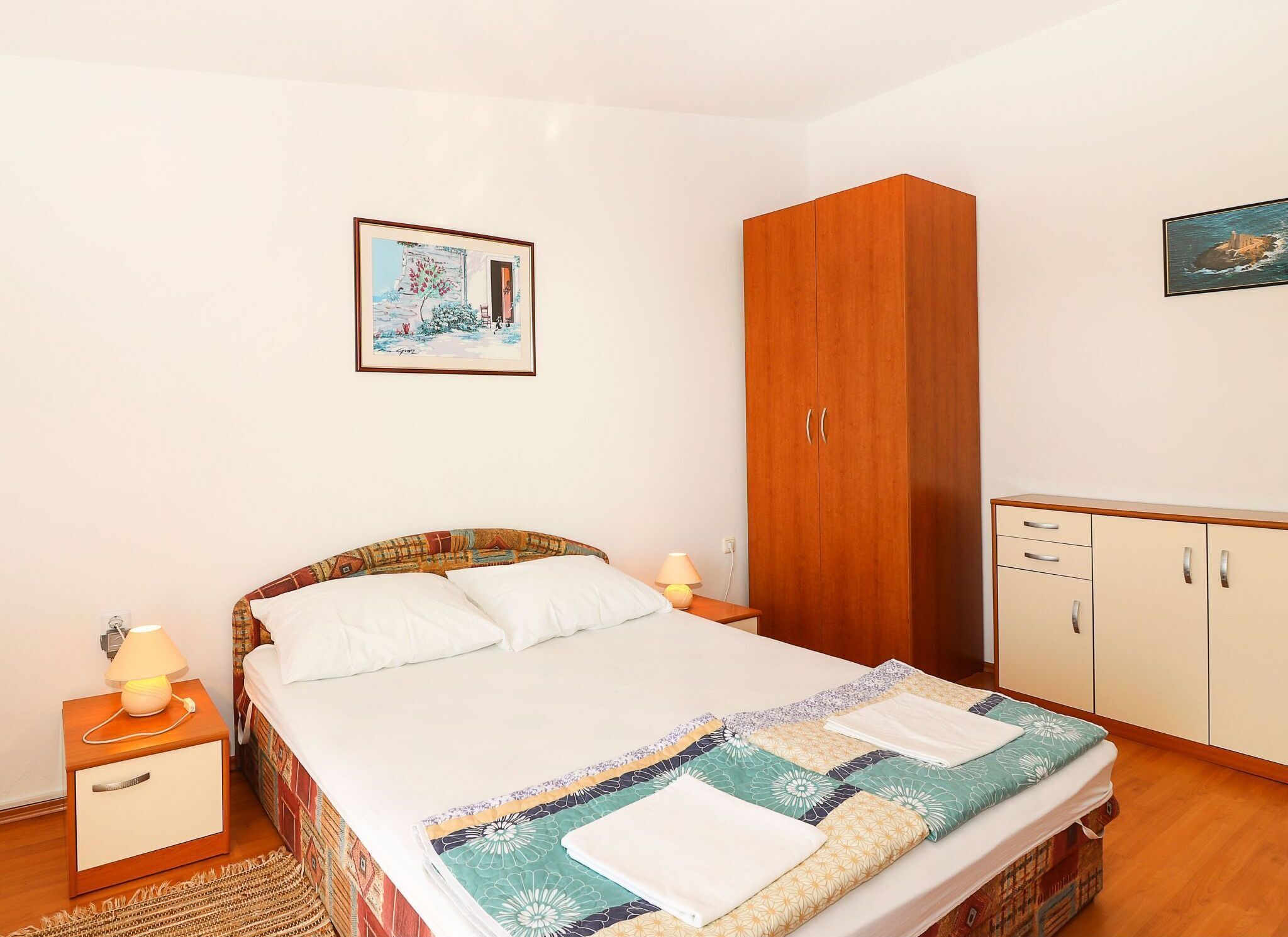 Une chambre à coucher avec un lit, une table de chevet, une armoire et un tableau accroché au mur.