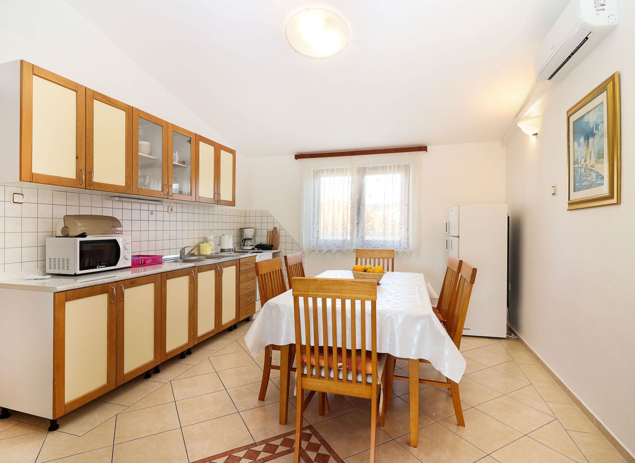 Cocina compacta con armarios de madera, microondas, lavamanos y una mesa de comedor para cuatro.