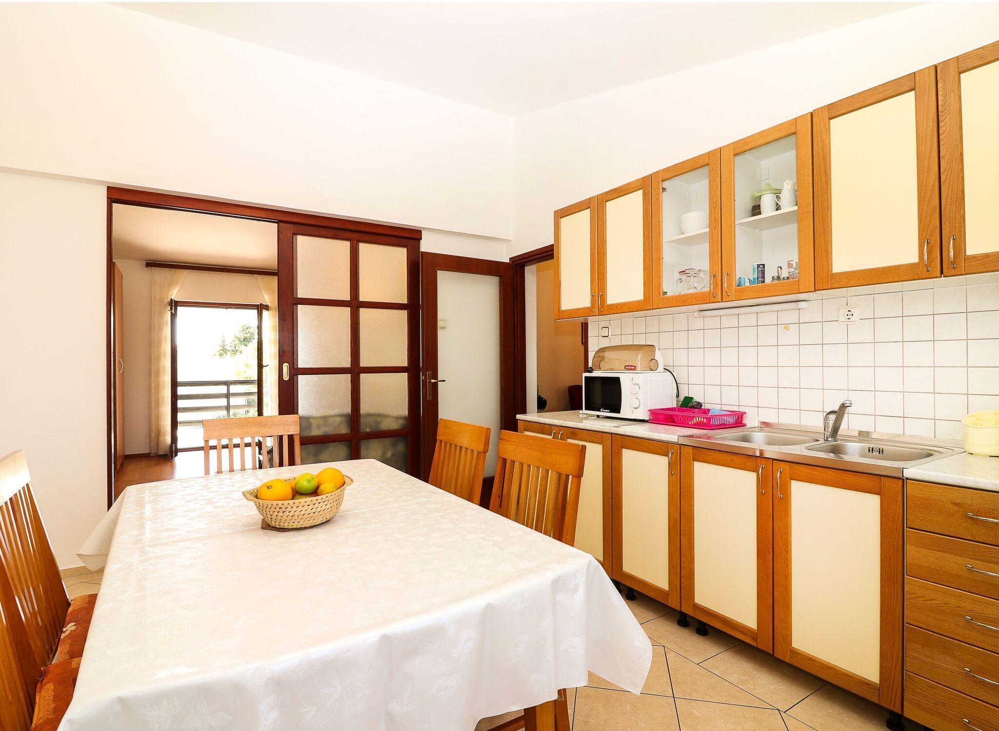 A compact kitchen with wooden cabinets, a microwave, and a dining area with a table set for two.