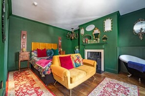 Une pièce comprenant un lit, un canapé, une cheminée et une baignoire.