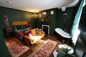 A room with a bed, a sofa, a fireplace, a bathtub, and a mirror. - One bedroom apartment in the heart of Whitby. Close to all local attractions. (Whitby)