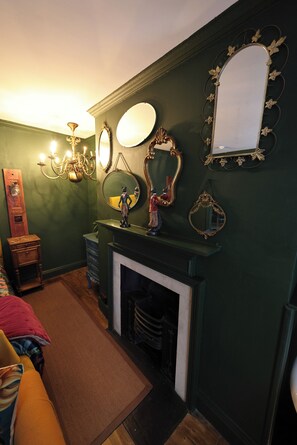A room with a fireplace, multiple mirrors, a chandelier, and a wooden dresser. - One bedroom apartment in the heart of Whitby. Close to all local attractions. (Whitby)