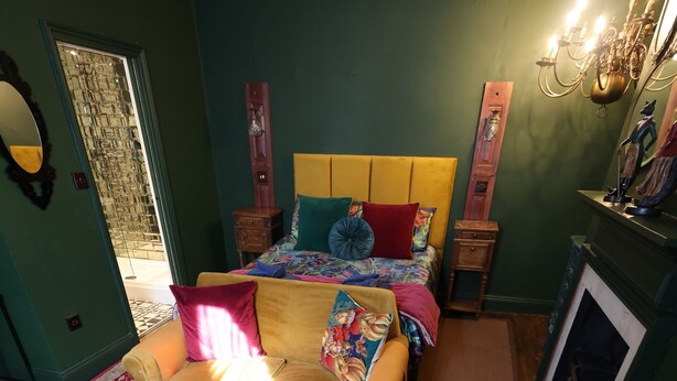 Een kamer met een bed, een slaapbank, een open haard en een spiegel.