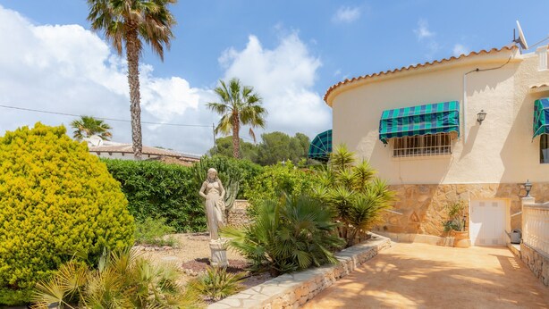A building with a stone facade, a statue in the garden, and a palm tree. - Casa Nuestro Sueño for 4 People (Calpe / Calp)