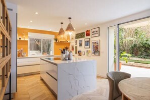 A modern kitchen with a marble island, pendant lighting, and artwork on the walls. - Ground floor of a villa with private entrance and pool in Saint-Paul-de-Vence (Saint-Paul-de-Vence)