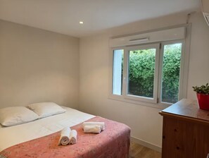 A bedroom with a bed, pillows, a window, and a wooden dresser. - Ground floor of a villa with private entrance and pool in Saint-Paul-de-Vence (Saint-Paul-de-Vence)