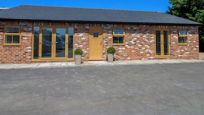 A brick building with large glass doors, a wooden door, and small windows. - Black Banks Farm Cottage (Darlington)