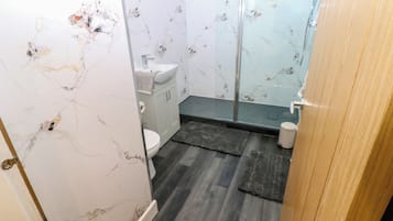 A bathroom with a toilet, sink, and shower area.