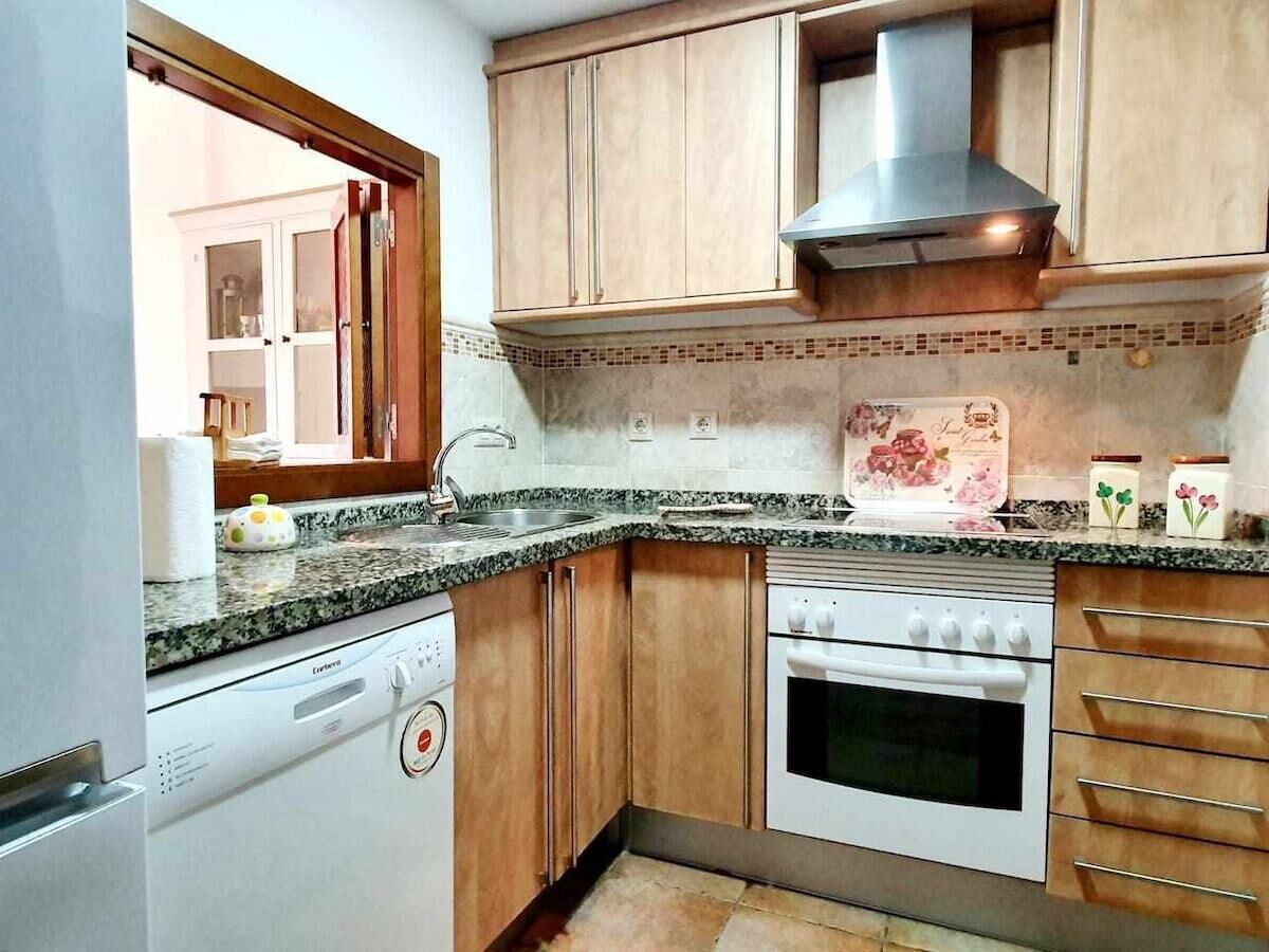 Una cocina compacta con lavavajillas, horno y armarios de madera.