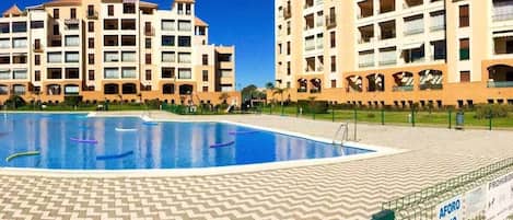 A hotel with a swimming pool, multiple balconies, and a sign indicating a capacity of 240 people.