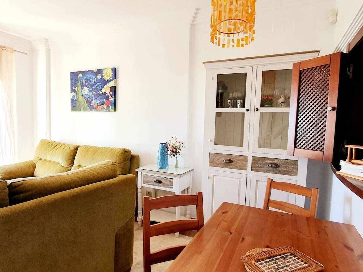 A living room with a sofa, a dining table, and a cabinet with glass doors.