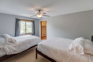 A bedroom with two beds, a ceiling fan, and a window with curtains. - Great MEA and Fall Getaway Lakefront Cabin (Cushing)