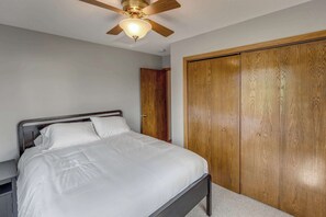 Un dormitorio con una cama, un armario de madera y un ventilador de techo.